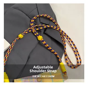 Detail of adjustable purple and orange braided strap on checkered canvas crossbody bag