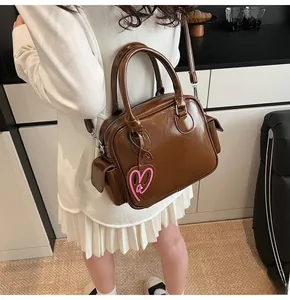 Close-up of a large brown glazed leather tote bag with heart charm and shoulder strap