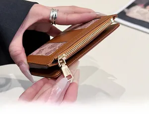 Dettaglio del portafoglio marrone con monogramma e chiusura lampo in metallo dorato liscio