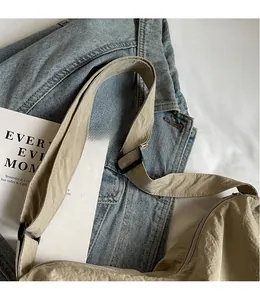 Close-up of light khaki nylon crossbody bag with adjustable wide strap and black zipper