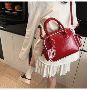 Detail of red patent leather bowling bag with white piping and heart charm in a kitchen setting