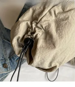 Detail of khaki nylon bag with drawstring cinch and black plastic cord adjuster