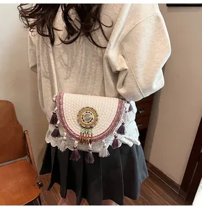 Detail view of bohemian straw bag with purple ethnic embroidery and dual-tone tassels