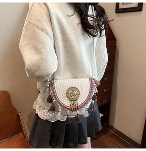 Detail of bohemian white woven crossbody bag featuring colorful ethnic bead embroidery and tassels