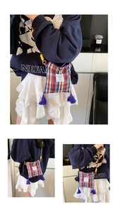 Detail of plaid canvas crossbody bag featuring colorful tassels and woven shoulder strap