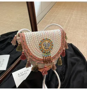 Detail of woven straw shoulder bag with colorful fringe tassels and bead embroidery