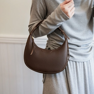 Dunkelbraune Halbmond-Schultertasche aus Leder mit Lychee-Muster an weiblichem Modell
