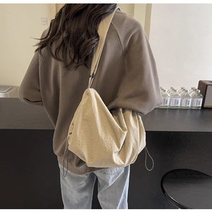 Rear view of a beige oversized nylon crossbody bag with side drawstring details