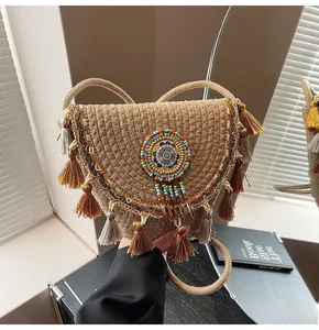Detail of bohemian straw crossbody bag with layered tassels and ethnic bead decoration