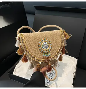 Detail of straw woven crossbody bag with bohemian tassels and ethnic beaded decor in a gift box