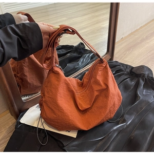 Detailed close-up of a brick red crescent moon crossbody bag with adjustable strap