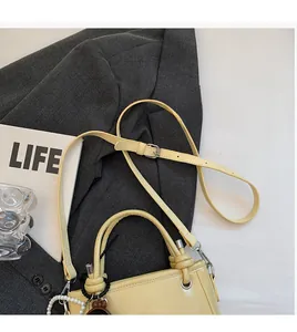 Detail of light yellow bucket bag with pearl charms and adjustable strap on a blazer
