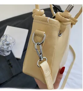 Detail of glossy bucket bag with silver hardware and unique knotted shoulder strap