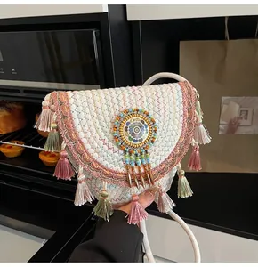 Detail of bohemian straw bag with colorful tassels, woven patterns and beadwork charm