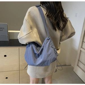 Blue large capacity drawstring crossbody bag shown on model for casual outdoor travel style