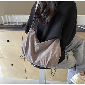 Detail view of large taupe hobo bag with rope trim on a casual lifestyle background