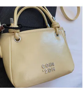 Close-up of minimalist cream leather bucket bag showing silver logo and soft texture