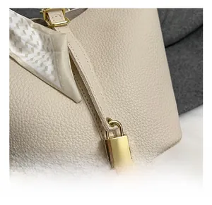 Makro-Detail der Beuteltasche aus Leder mit Narbenstruktur, Goldschloss und Seidenschal