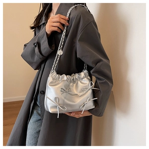 Detail of silver pleated bucket bag with bow decorations and metallic chain strap