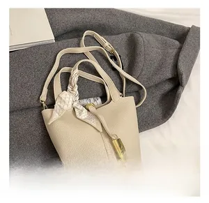 Detail der beigen Handtasche aus Leder mit Seidenschal-Griff und goldenem Vorhängeschloss
