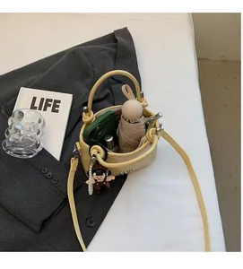 Detail view of the yellow leather bucket bag showing interior space for umbrella and phone