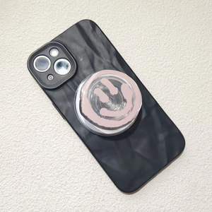 Detail of pink smiley face phone grip mounted on a black wave texture phone case