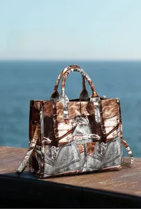 Close-up of vintage denim and brown leather patchwork tote bag on a beach pier