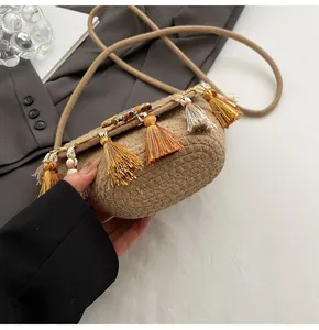 Detail view of woven straw bag with colorful tassels and beads held by a fashion model
