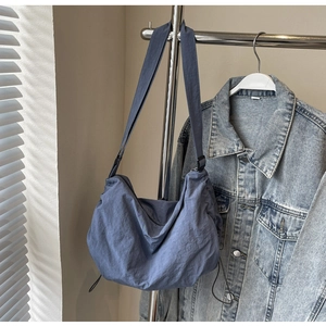 Detail of grey-blue nylon hobo bag featuring drawstring bottom and adjustable strap