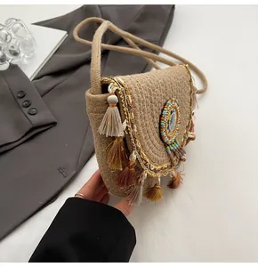 Detailed view of woven straw shoulder bag with colorful tassels and beaded emblem
