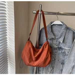 Detail of burnt orange nylon crescent bag with adjustable strap and side drawstrings