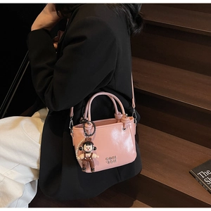 Rosa Bucket Bag mit süßem Bären-Anhänger und Perlenkette zu einem schwarzen Blazer