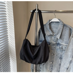 Detail view of large black canvas crossbody bag with adjustable wide strap and pleated design