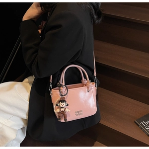 Pink glossy bucket bag with GOTH letter embossing and cute cartoon boy charm detail