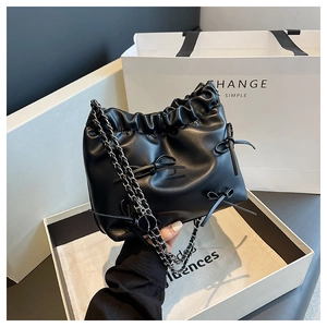 Detail of black pleated cloud bucket bag with leather bows and silver chain strap