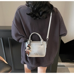 Silberne strukturierte Eimertasche mit Anhänger und Perlenkette am Modell