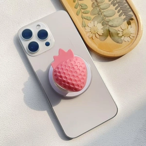 Close-up of pink strawberry resin phone grip on a white smartphone for desk support