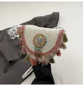 Detail of bohemian straw bag featuring colorful tassels and circular bead embroidery