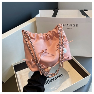 Detail of pink pleated tote bag featuring delicate ribbon bows and metal chain strap