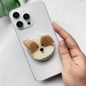 Close-up of a cute acrylic puppy phone grip attached to a white smartphone back