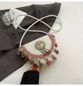 Detail of bohemian straw crossbody bag with colorful fringe and beaded ethnic ornament