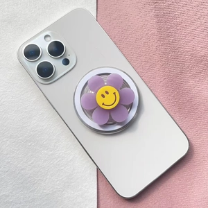 Detail of cute purple flower smiling face magnetic pop socket on white smartphone back