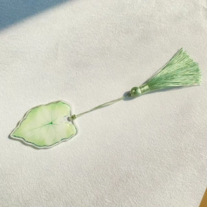 Detailed view of an acrylic leaf bookmark with green leaf patterns and a silk tassel