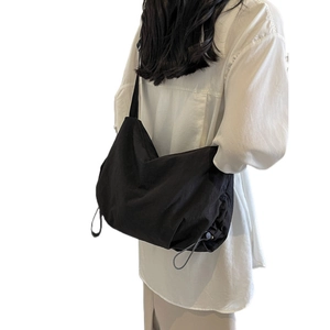 Large black nylon crossbody bag in Japanese utility style shown on a model in white