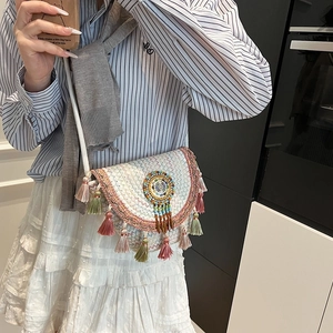 Bohemian woven straw shoulder bag featuring colorful tassels and beadwork on a model