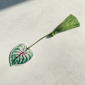Detailed macro view of acrylic leaf bookmark with vibrant red veins and green silk tassel