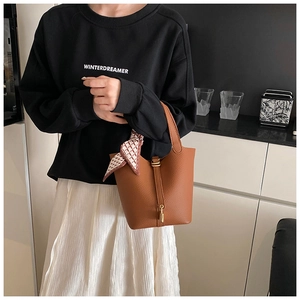 Detailaufnahme der braunen Bucket Bag aus Leder mit Schloss und Seidenschal-Dekor