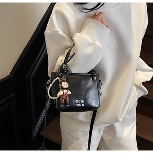 Detail of black mini bucket bag with COIH '2DN print, cartoon charm and pearl chain decoration