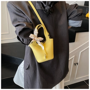 Detailansicht der zitronengelben Beuteltasche mit Litschistruktur und Seidenschal
