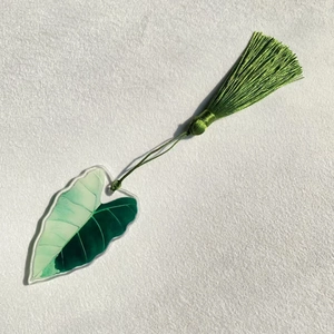 Detail of green acrylic leaf bookmark with matching silk tassel on white textured paper